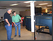 Students checking their vertical ding repair work on a pickup truck bed